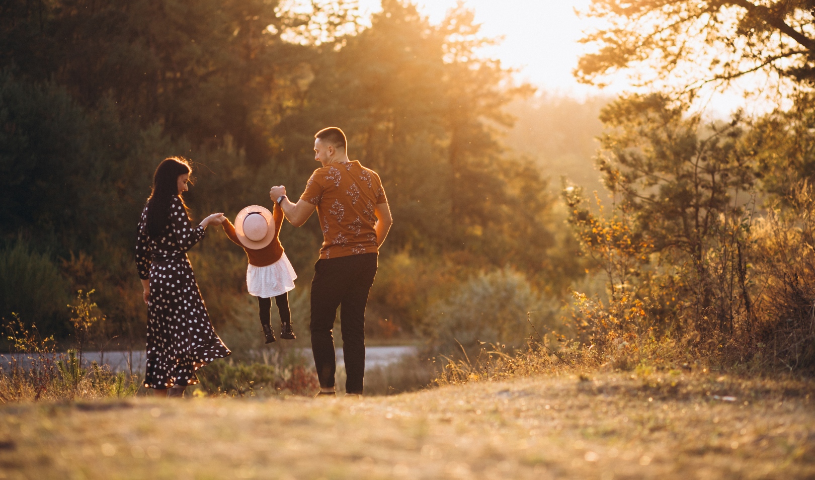 Obitelj u šetnji prirodom za vrijeme zalaska sunca, simbolizira financijsku neovisnost i ciljeve rane mirovine.